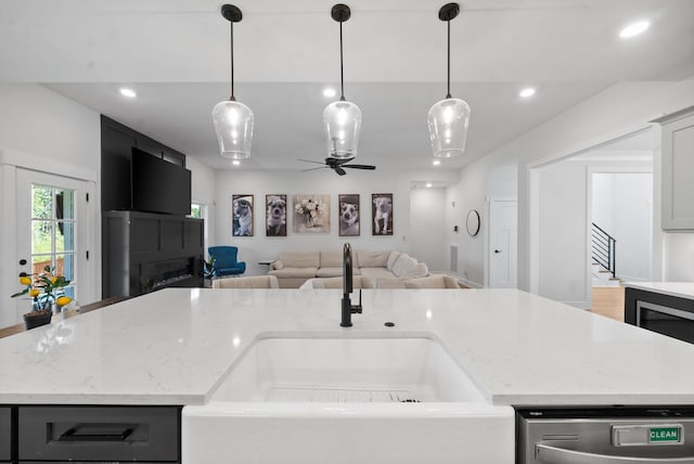 kitchen with ceiling fan, an island with sink, decorative light fixtures, and sink