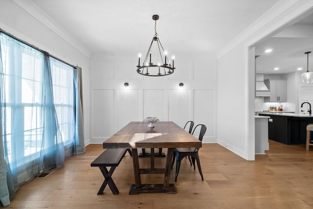 dining room with a notable chandelier, light wood-type flooring, ornamental molding, and a wealth of natural light