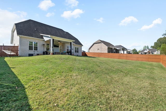 rear view of property featuring a lawn, a patio, and ceiling fan