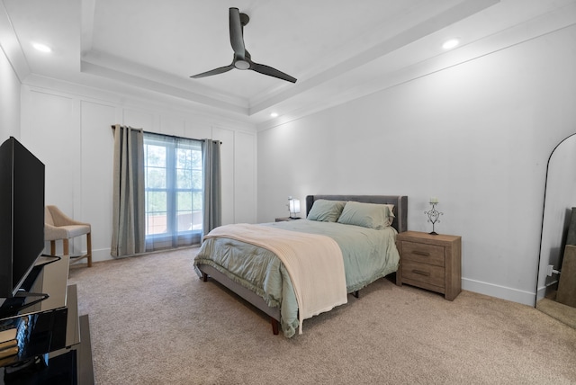 carpeted bedroom featuring ceiling fan, a raised ceiling, and crown molding