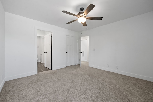 unfurnished bedroom with ceiling fan, ensuite bath, and dark carpet