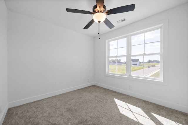 carpeted empty room with ceiling fan and plenty of natural light