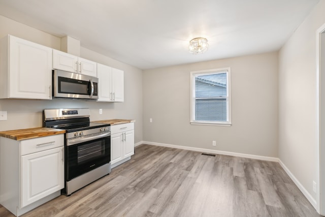 kitchen with butcher block countertops, stainless steel appliances, light hardwood / wood-style floors, and white cabinets