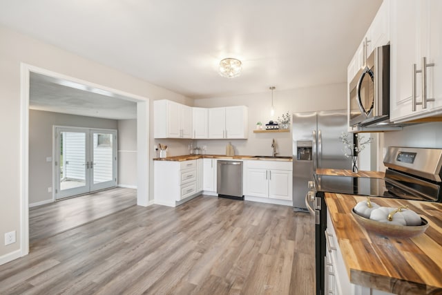 kitchen featuring wood counters, white cabinetry, light hardwood / wood-style floors, stainless steel appliances, and decorative light fixtures