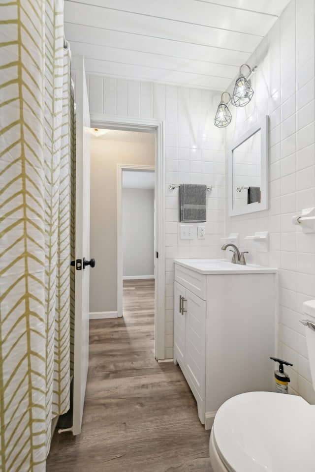 bathroom featuring toilet, hardwood / wood-style floors, vanity, and tile walls