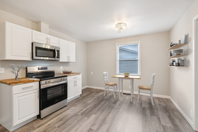 kitchen with white cabinetry, butcher block countertops, stainless steel appliances, and light hardwood / wood-style floors