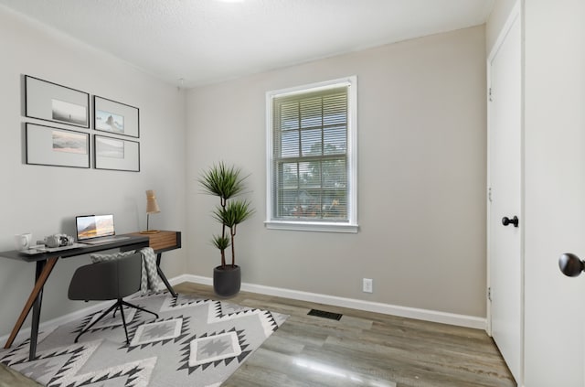 home office featuring a textured ceiling and light hardwood / wood-style floors