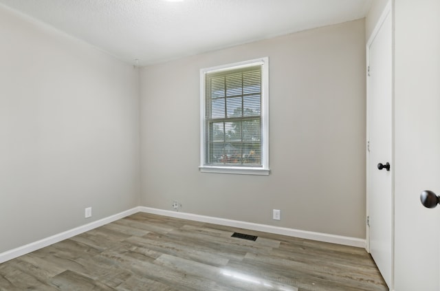 unfurnished room with light hardwood / wood-style flooring and a textured ceiling