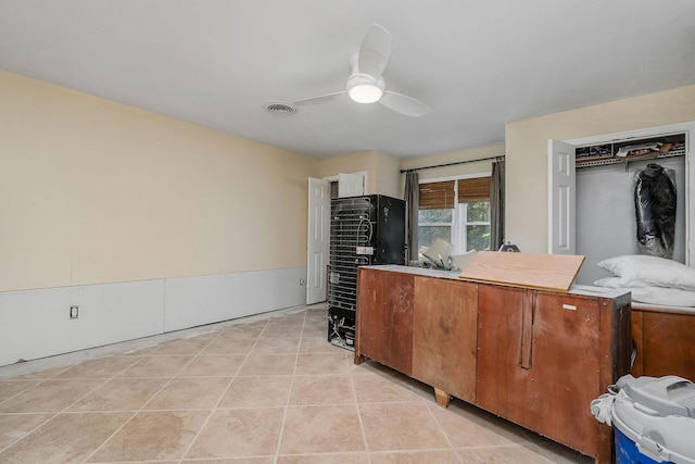 kitchen featuring brown cabinets, light tile patterned floors, light countertops, visible vents, and a ceiling fan