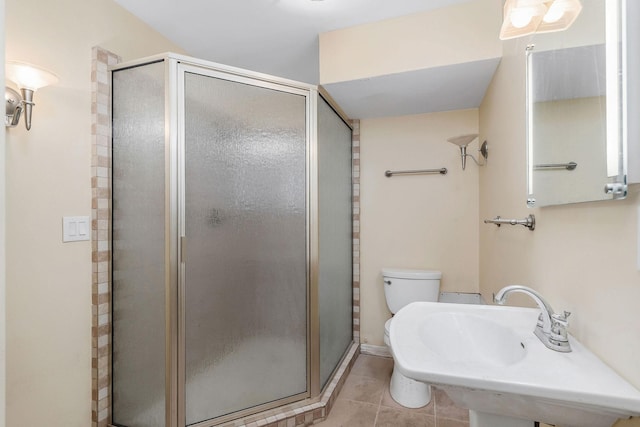 bathroom featuring a stall shower, tile patterned flooring, a sink, and toilet