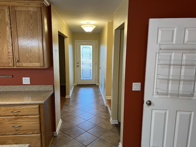 doorway with light tile patterned flooring and baseboards