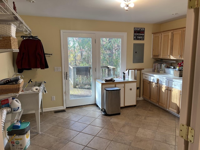 kitchen with light tile patterned floors, electric panel, visible vents, baseboards, and light countertops