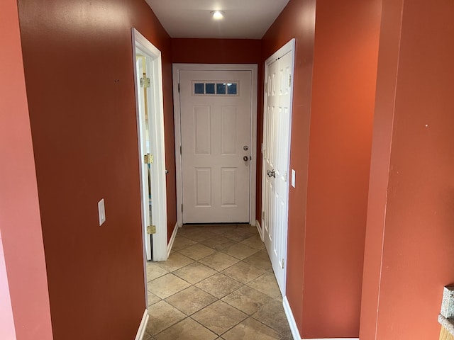 corridor with baseboards and light tile patterned floors