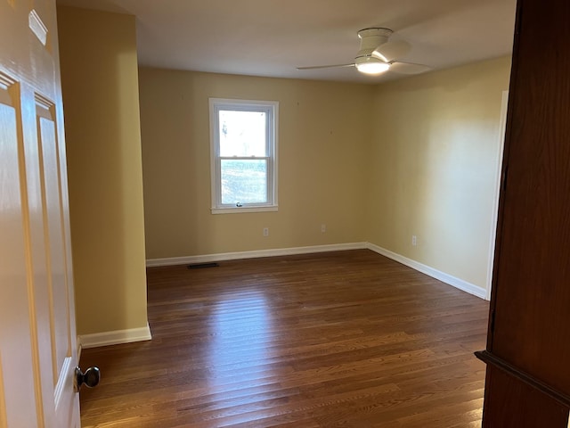 unfurnished room with ceiling fan, baseboards, visible vents, and dark wood finished floors