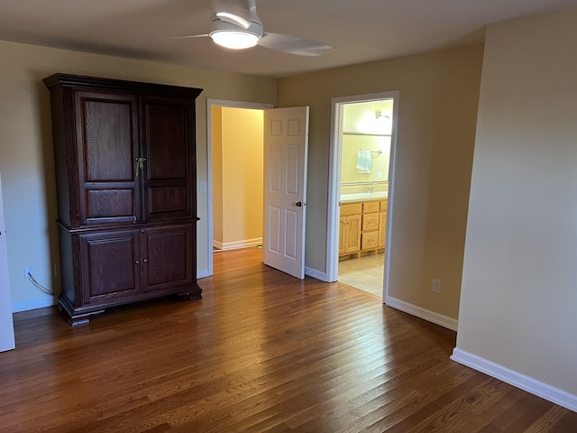 unfurnished bedroom featuring a sink, dark wood-type flooring, connected bathroom, and baseboards