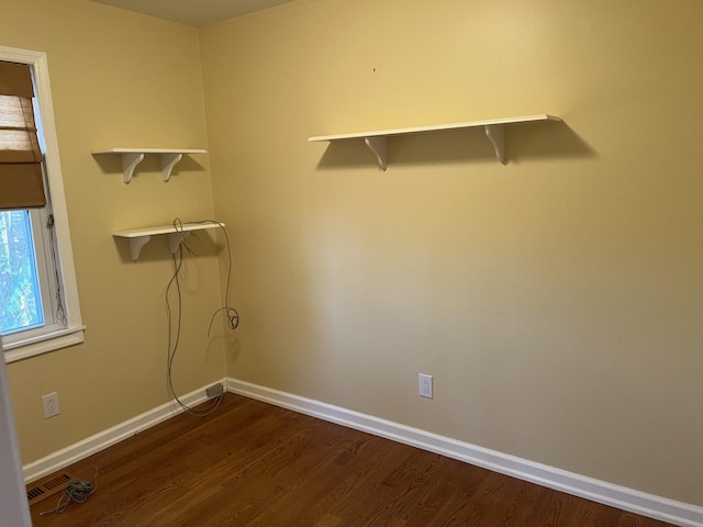 clothes washing area featuring dark wood-type flooring and baseboards