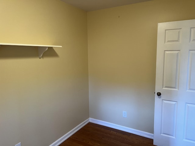 empty room with dark wood-style flooring and baseboards