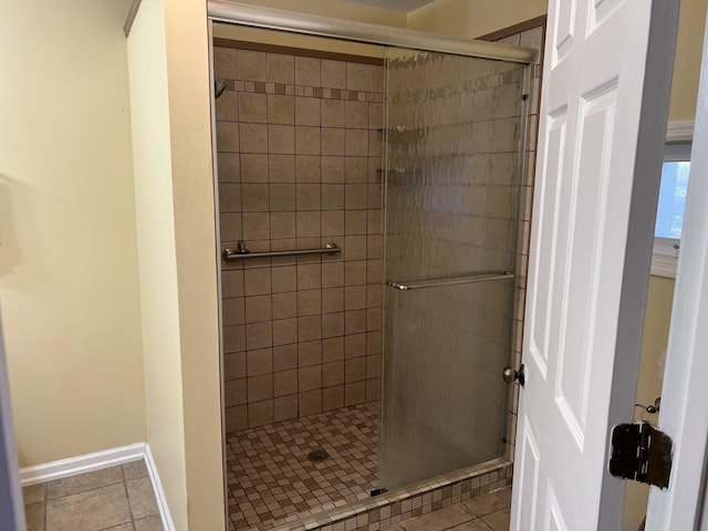 bathroom featuring tile patterned flooring, tiled shower, and baseboards