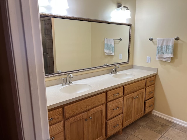 full bath featuring double vanity, tile patterned flooring, baseboards, and a sink