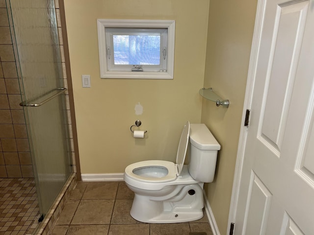 full bath featuring tile patterned floors, a tile shower, toilet, and baseboards