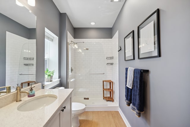 bathroom with a shower with shower door, hardwood / wood-style flooring, vanity, and toilet