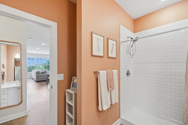 bathroom featuring a tile shower, hardwood / wood-style flooring, and vanity