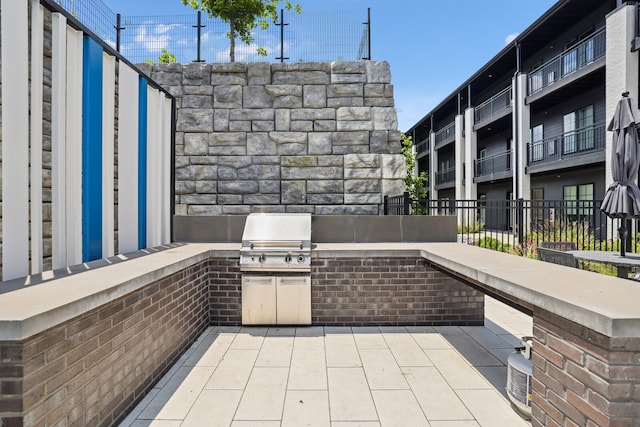 view of patio with grilling area, a balcony, and exterior kitchen