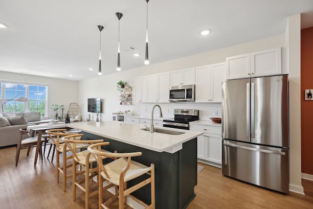 kitchen featuring decorative light fixtures, appliances with stainless steel finishes, light hardwood / wood-style floors, and white cabinetry