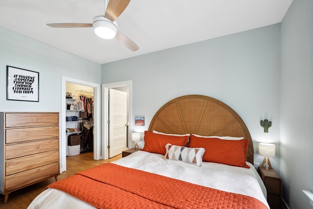 bedroom with a spacious closet, a closet, ceiling fan, and hardwood / wood-style flooring