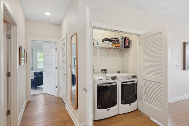 clothes washing area featuring washing machine and dryer and light hardwood / wood-style flooring