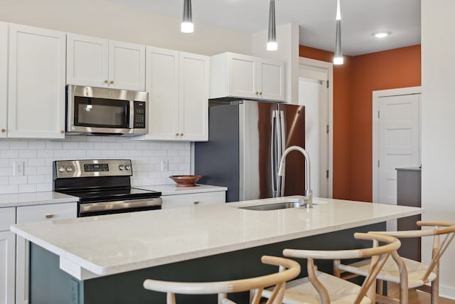 kitchen featuring stainless steel appliances, hanging light fixtures, and a kitchen island with sink