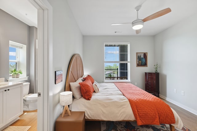 bedroom with multiple windows, ceiling fan, light hardwood / wood-style flooring, and ensuite bath