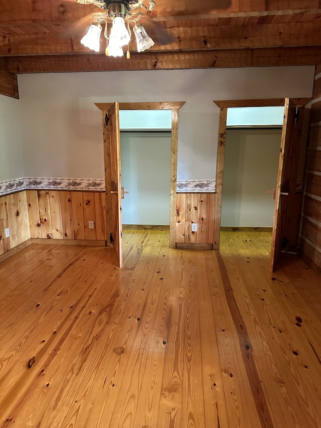 empty room featuring ceiling fan, beamed ceiling, light hardwood / wood-style flooring, and wood ceiling