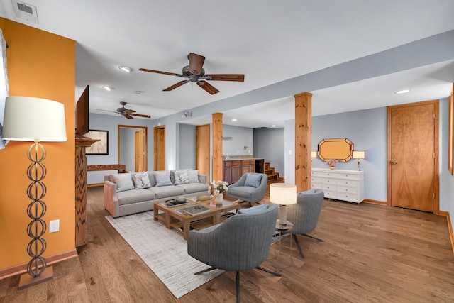 living room featuring ornate columns, hardwood / wood-style floors, and ceiling fan