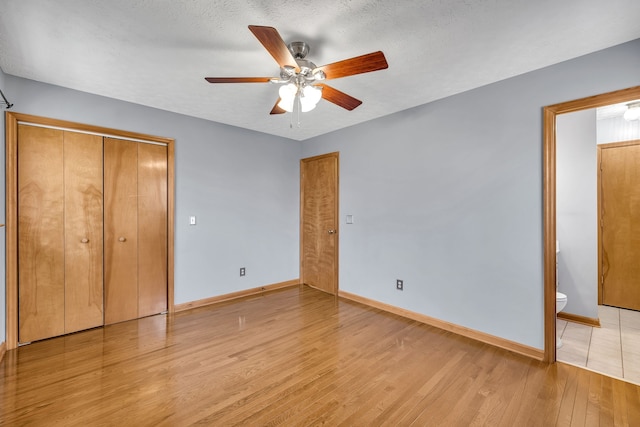 unfurnished bedroom featuring ceiling fan, light hardwood / wood-style flooring, a closet, connected bathroom, and a textured ceiling