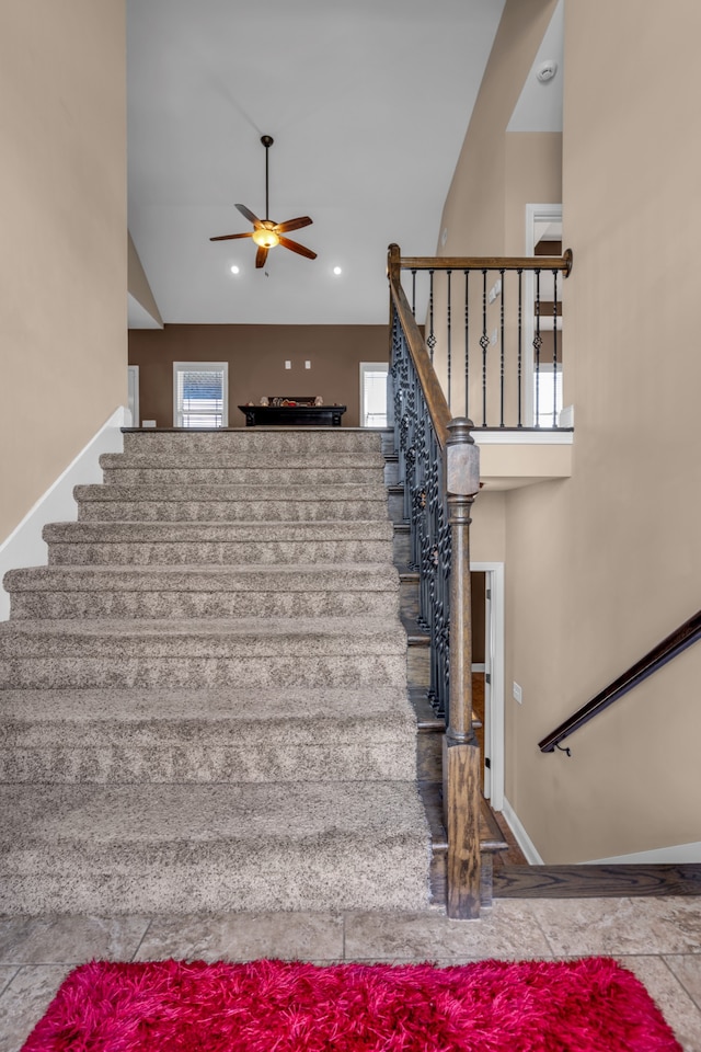 stairs with ceiling fan and high vaulted ceiling