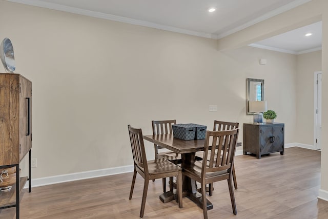 dining space with crown molding and light hardwood / wood-style floors