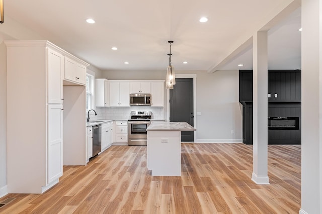 kitchen featuring stainless steel appliances, decorative backsplash, light wood-style flooring, and a sink