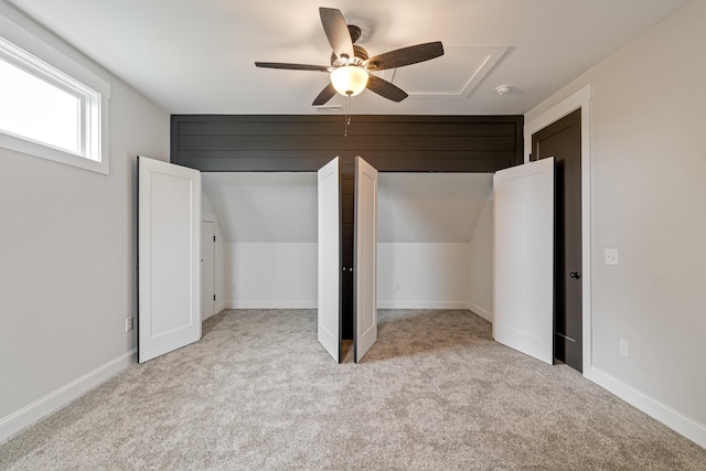 unfurnished bedroom with attic access, a ceiling fan, and carpet floors