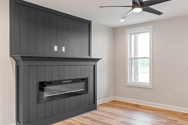 interior space featuring ceiling fan, a large fireplace, visible vents, baseboards, and light wood-type flooring