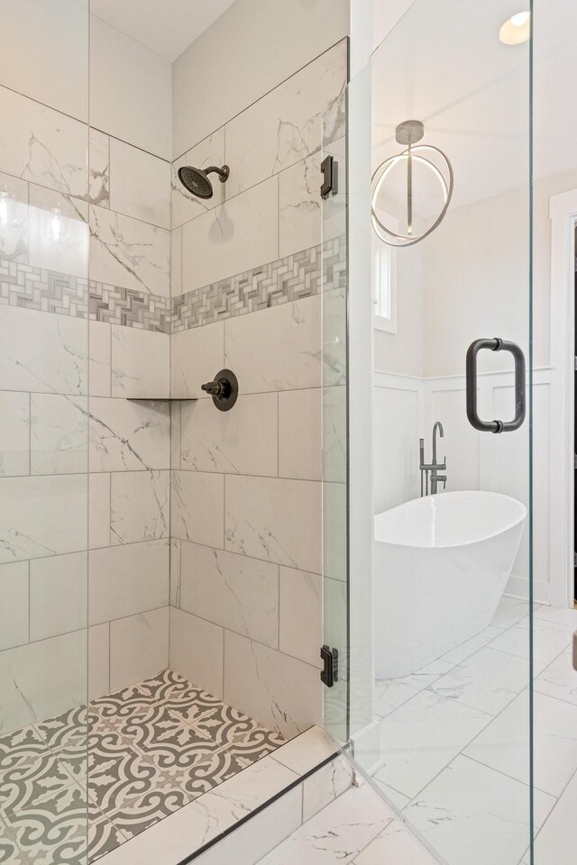 bathroom with a stall shower, marble finish floor, and a freestanding bath