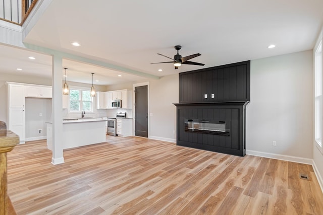 unfurnished living room with recessed lighting, a ceiling fan, light wood-style flooring, and baseboards