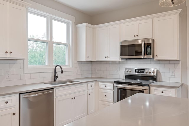 kitchen with stainless steel appliances, light countertops, white cabinets, and a sink