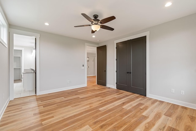 unfurnished bedroom featuring recessed lighting, light wood finished floors, ensuite bath, and baseboards
