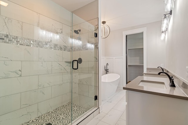 full bathroom featuring wainscoting, a shower stall, marble finish floor, a freestanding tub, and vanity
