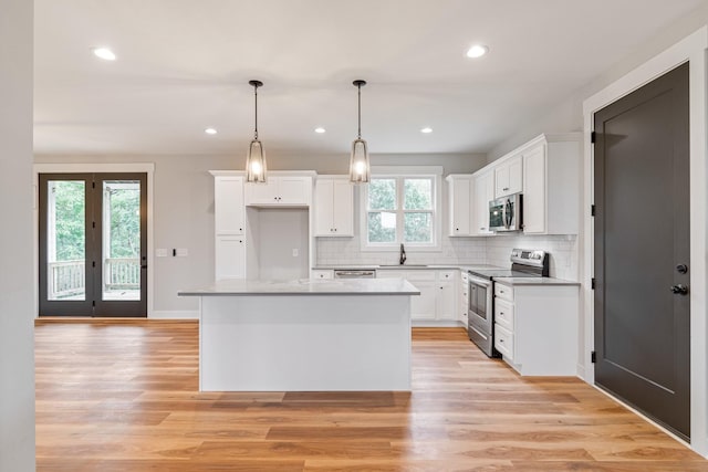 kitchen featuring white cabinetry, tasteful backsplash, a sink, stainless steel appliances, and a kitchen island