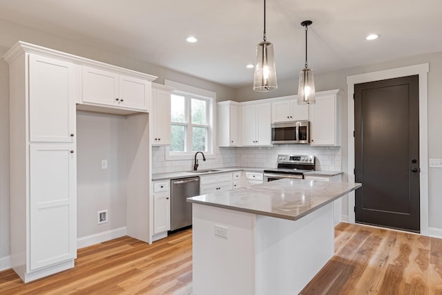 kitchen with light wood finished floors, a sink, white cabinets, and stainless steel appliances
