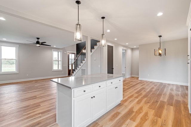 kitchen with white cabinetry, a center island, open floor plan, and light wood finished floors