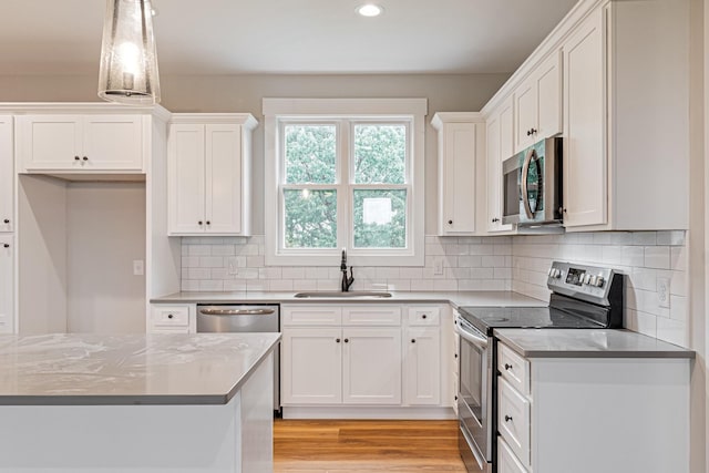 kitchen featuring appliances with stainless steel finishes, white cabinetry, recessed lighting, and a sink