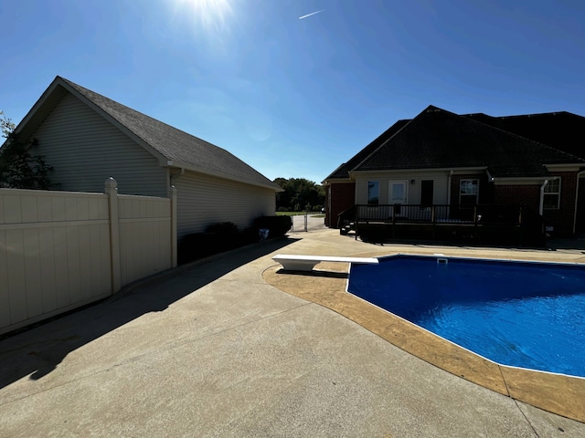 view of swimming pool featuring a patio and a diving board